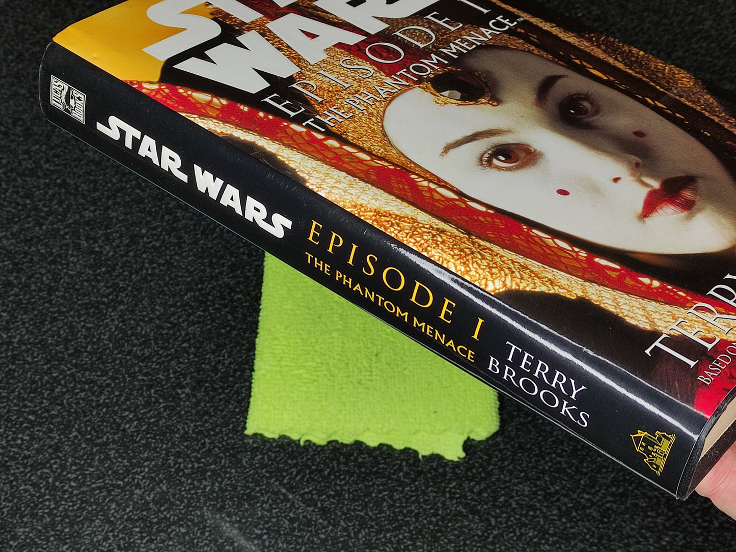 Book titled 'Star Wars Episode I: The Phantom Menace' by Terry Brooks on a dark surface with a green cloth underneath.
