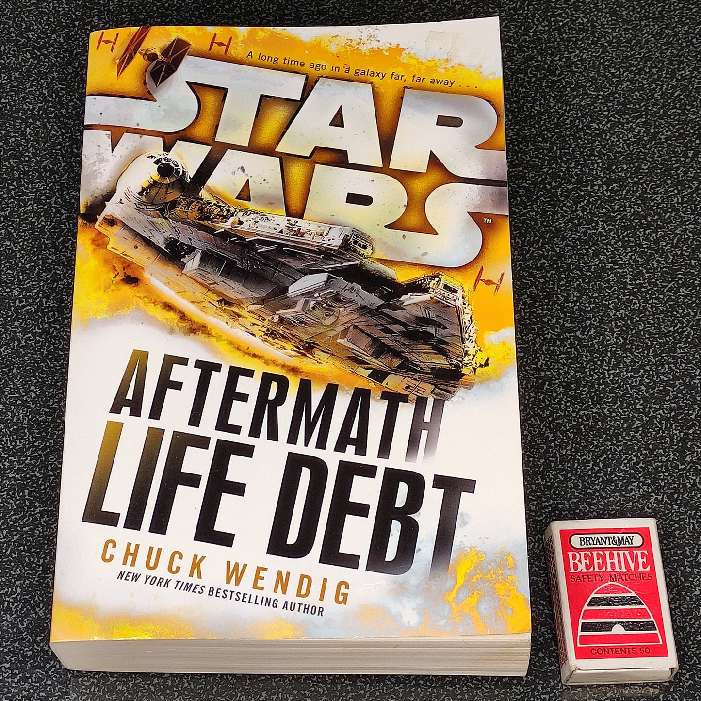 Book titled 'Aftermath: Life Debt' by Chuck Wendig with a Star Wars logo on a textured surface.