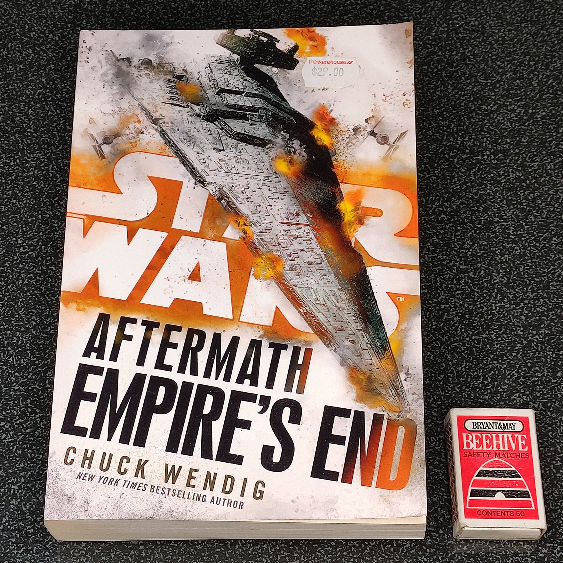 Book titled 'Aftermath: Empire's End' by Chuck Wendig on a textured black surface.