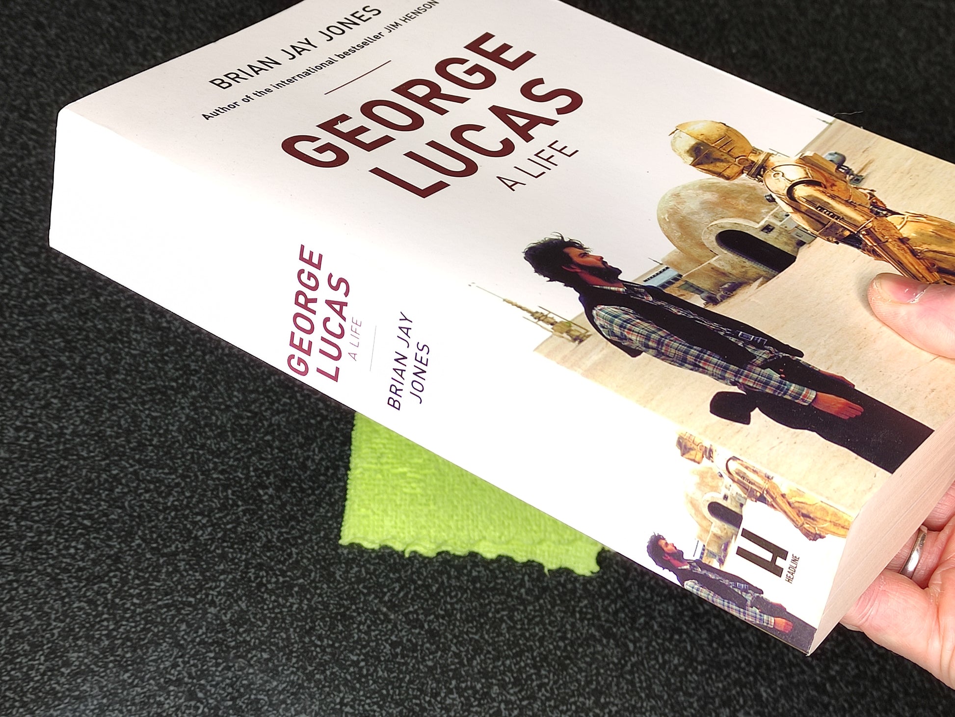 Book titled 'George Lucas: Alive' held by a hand on a dark surface