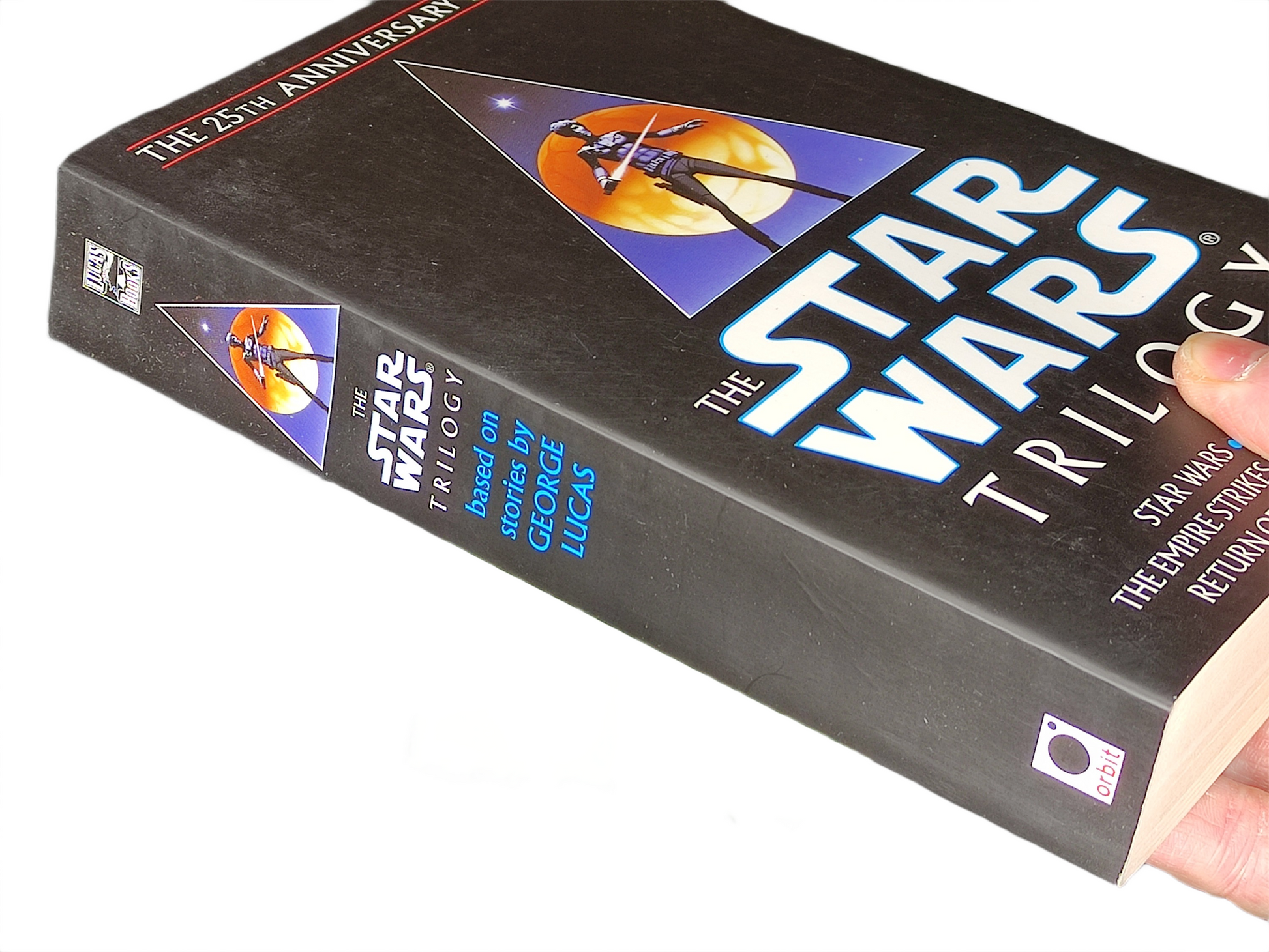 Book titled 'The Star Wars Trilogy' held by a hand on a white background