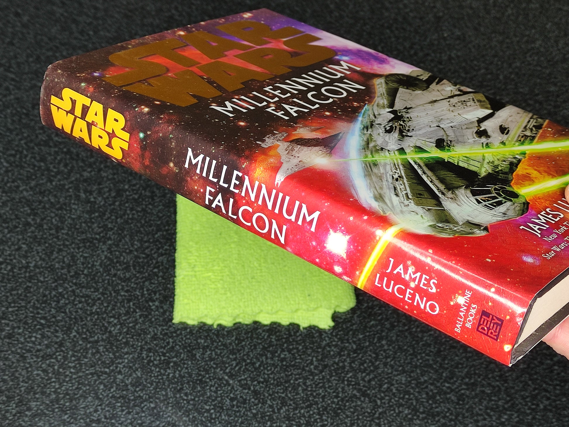 Book titled 'Millennium Falcon' by James Luceno on a dark surface with a green cloth underneath.