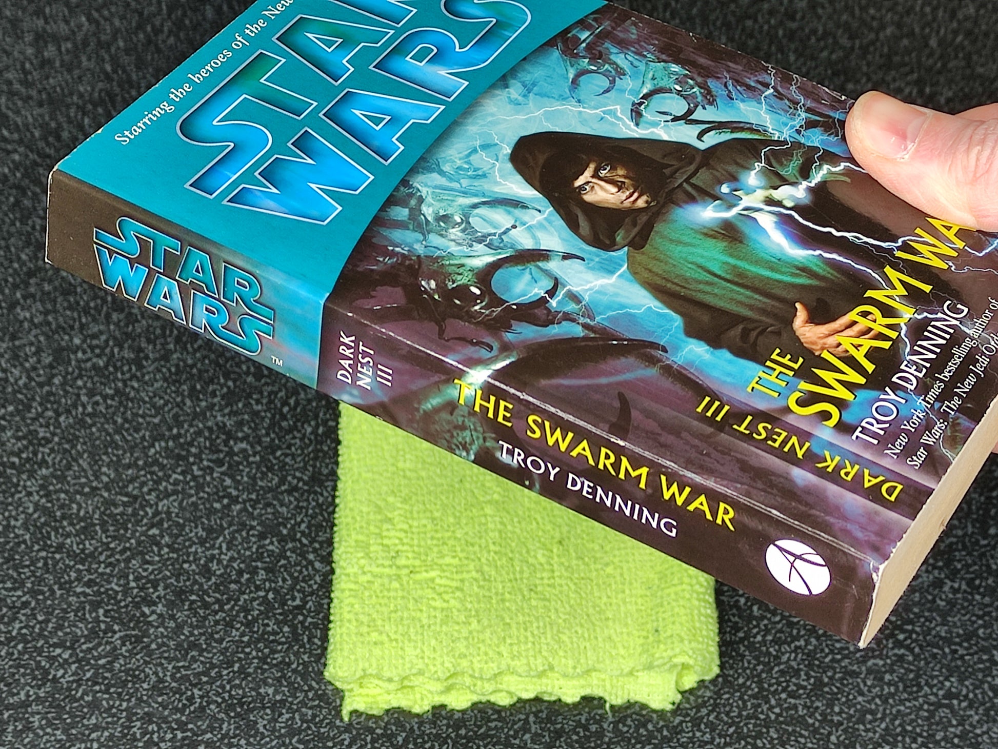 Book titled 'The Swarm War' by Troy Denning with a Star Wars branded book next to it on a dark surface.