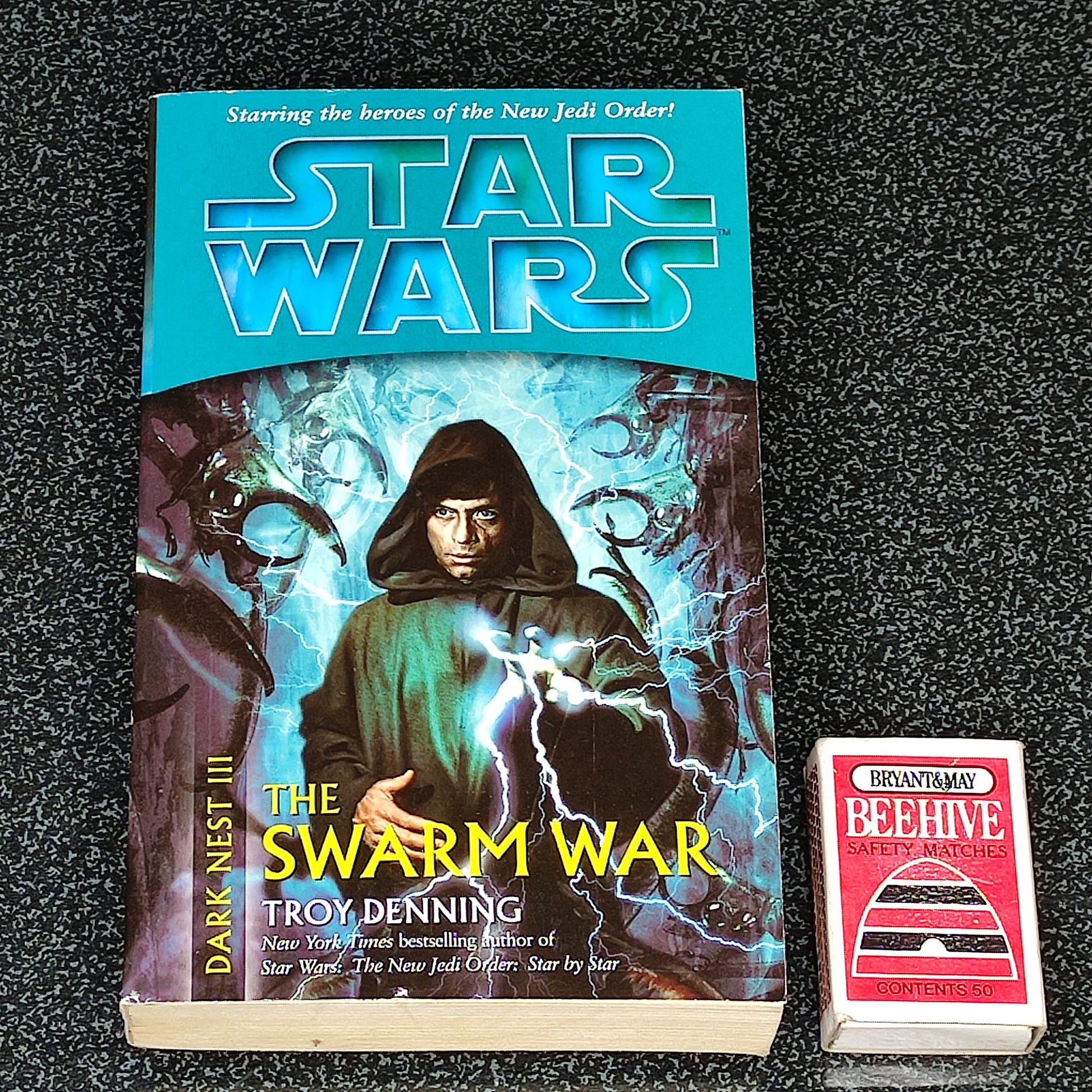 Book titled 'The Swarm War' by Troy Denning with a Star Wars logo on a dark textured surface.