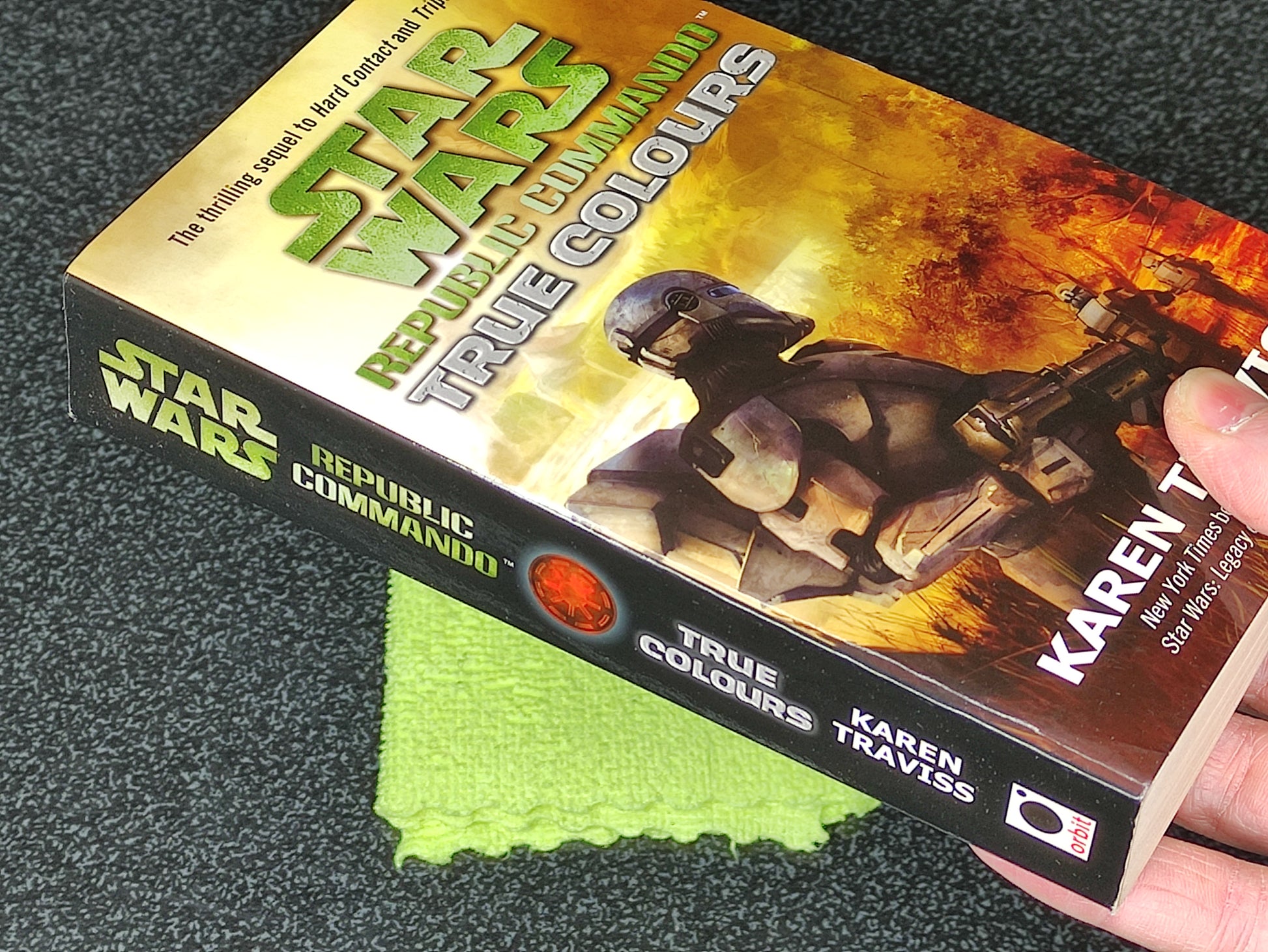 Book titled 'True Colours' from the Star Wars Republic Commando series held by a hand on a textured surface.
