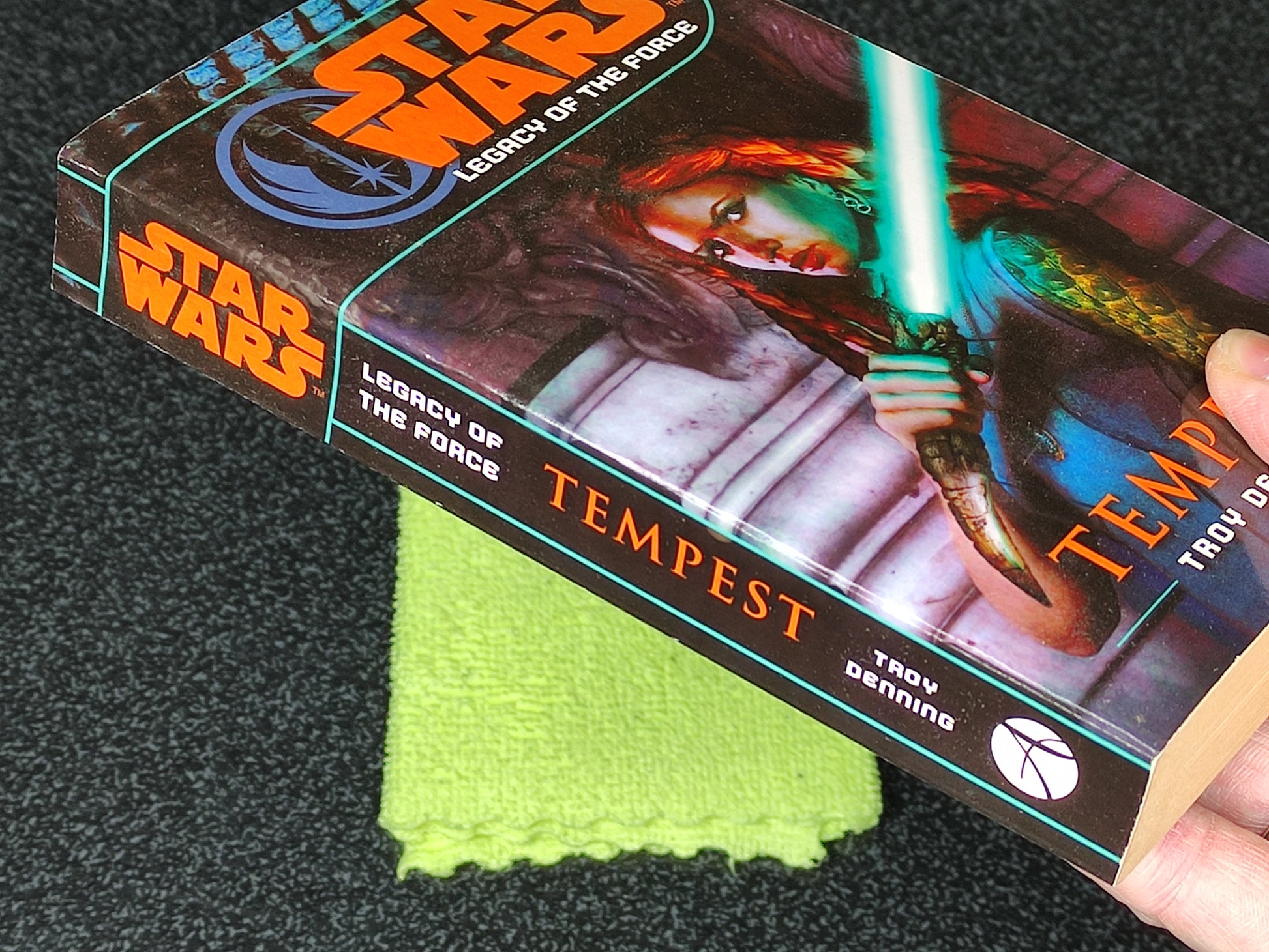 Book titled 'Tempest' from the 'Star Wars' series held by a hand on a dark surface.