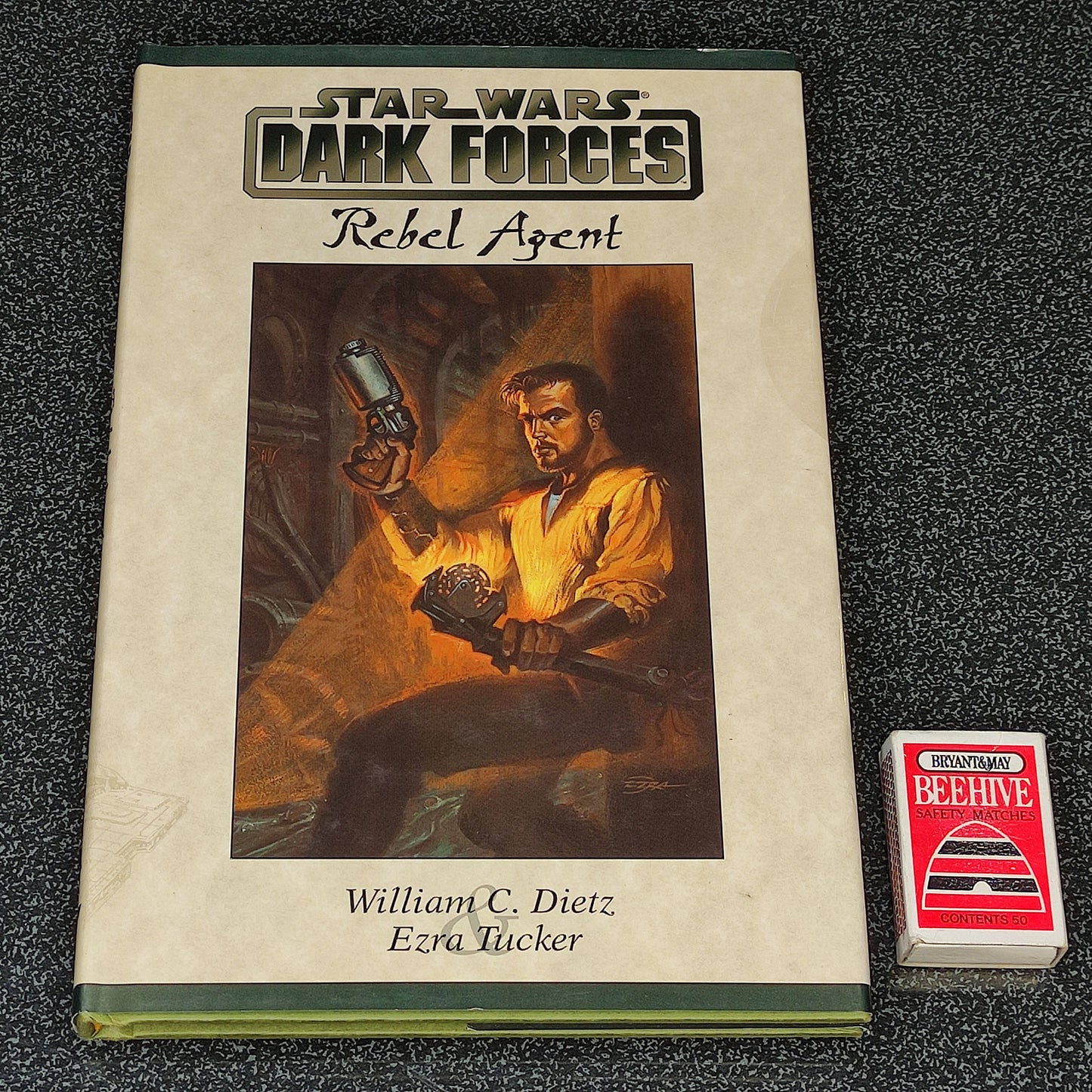 Book titled 'Star Wars: Dark Forces Rebel Agent' with a character illustration on the cover, placed next to a small red and white box.