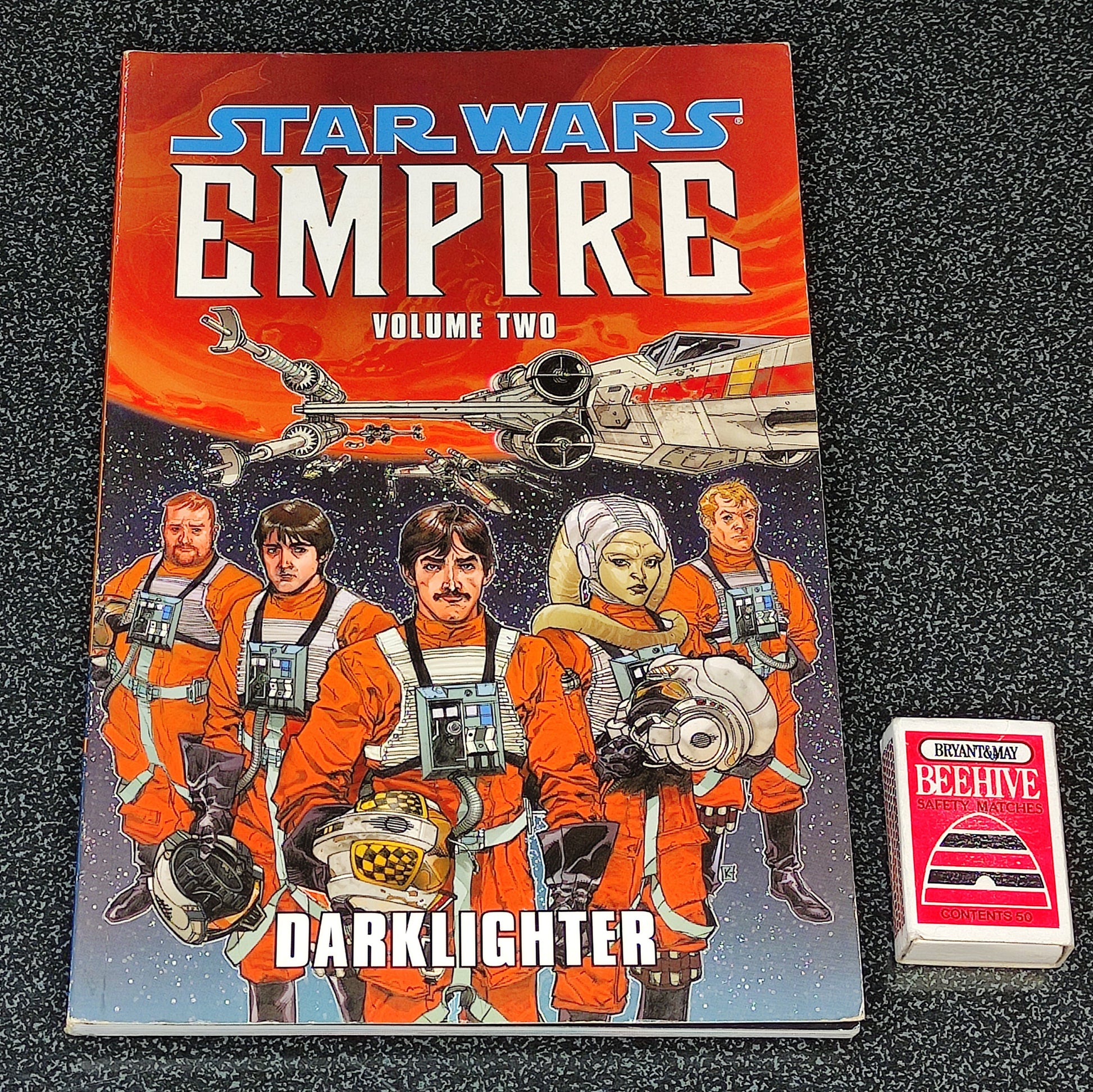 Star Wars 'Empire' comic book Volume Two on a dark textured surface with a small card beside it.