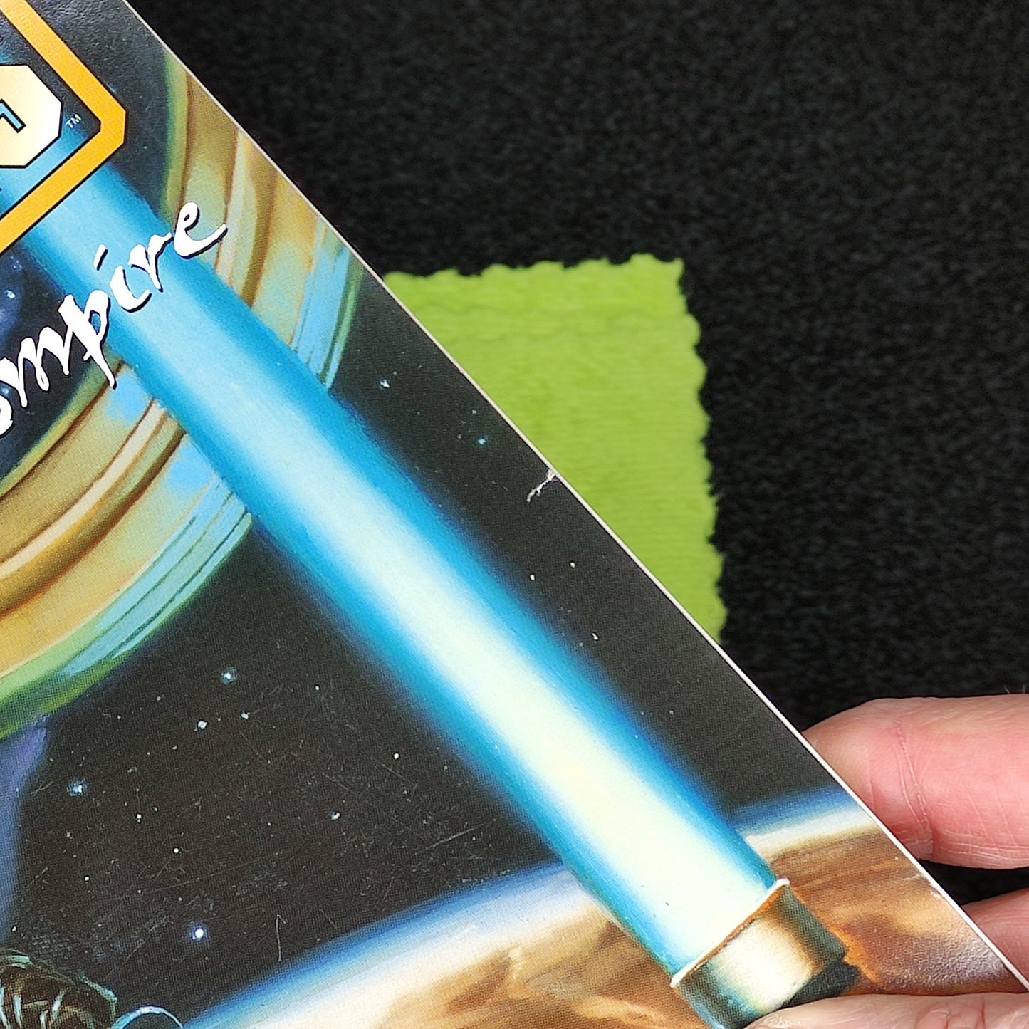 Person holding a 'Star Wars Forces of the Empire' book with a blue lightsaber