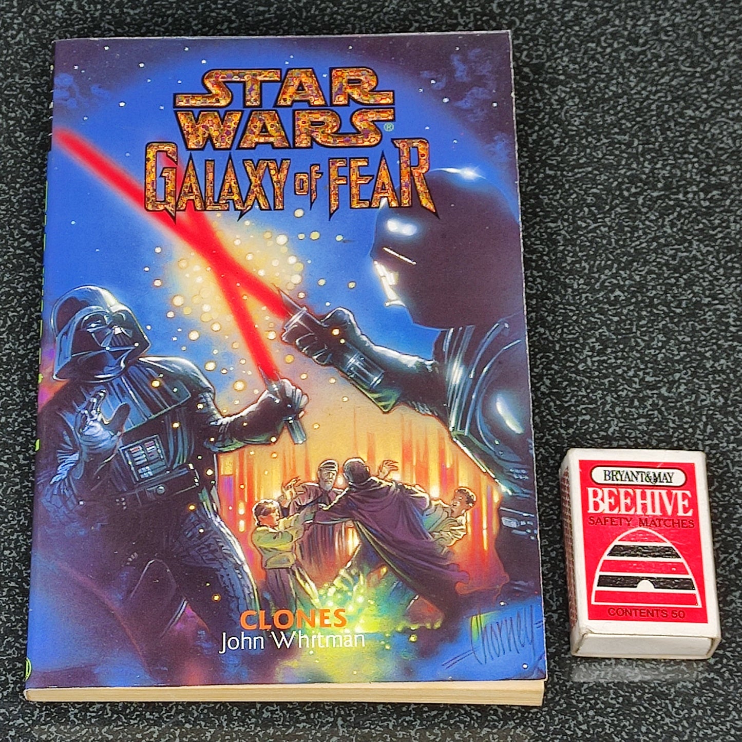 Book titled 'Star Wars: Galaxy of Fear' with a small red and white card on a dark textured surface