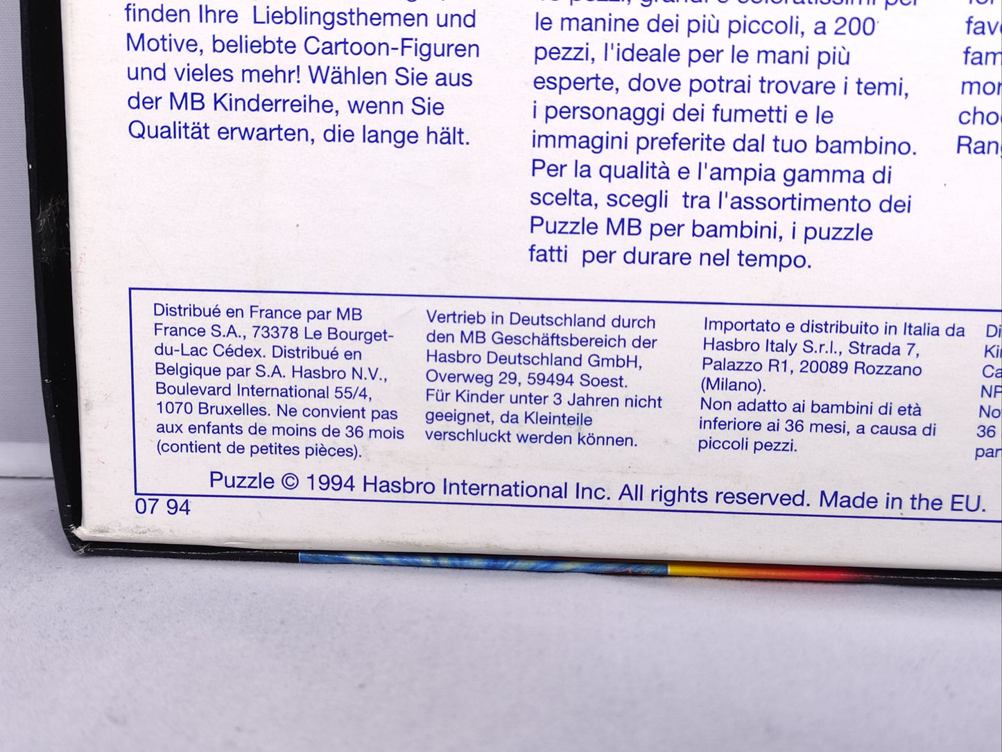 Close-up of a toy box label with text in multiple languages on a gray surface.