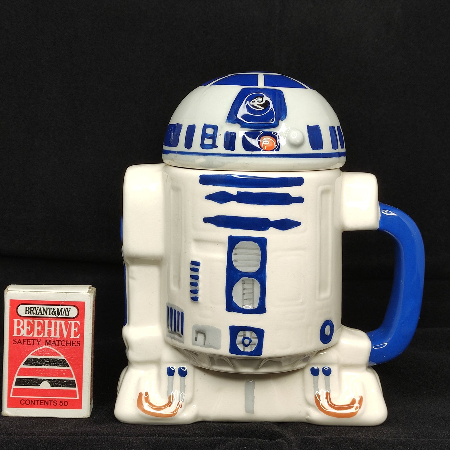 R2-D2 mug from Star Wars with a small box labeled 'Beehive' on a black background