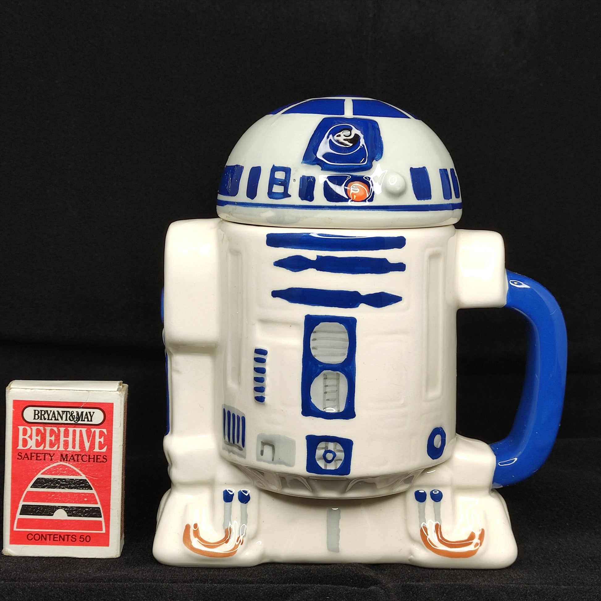 R2-D2 mug from Star Wars with a small box labeled 'Beehive' on a black background
