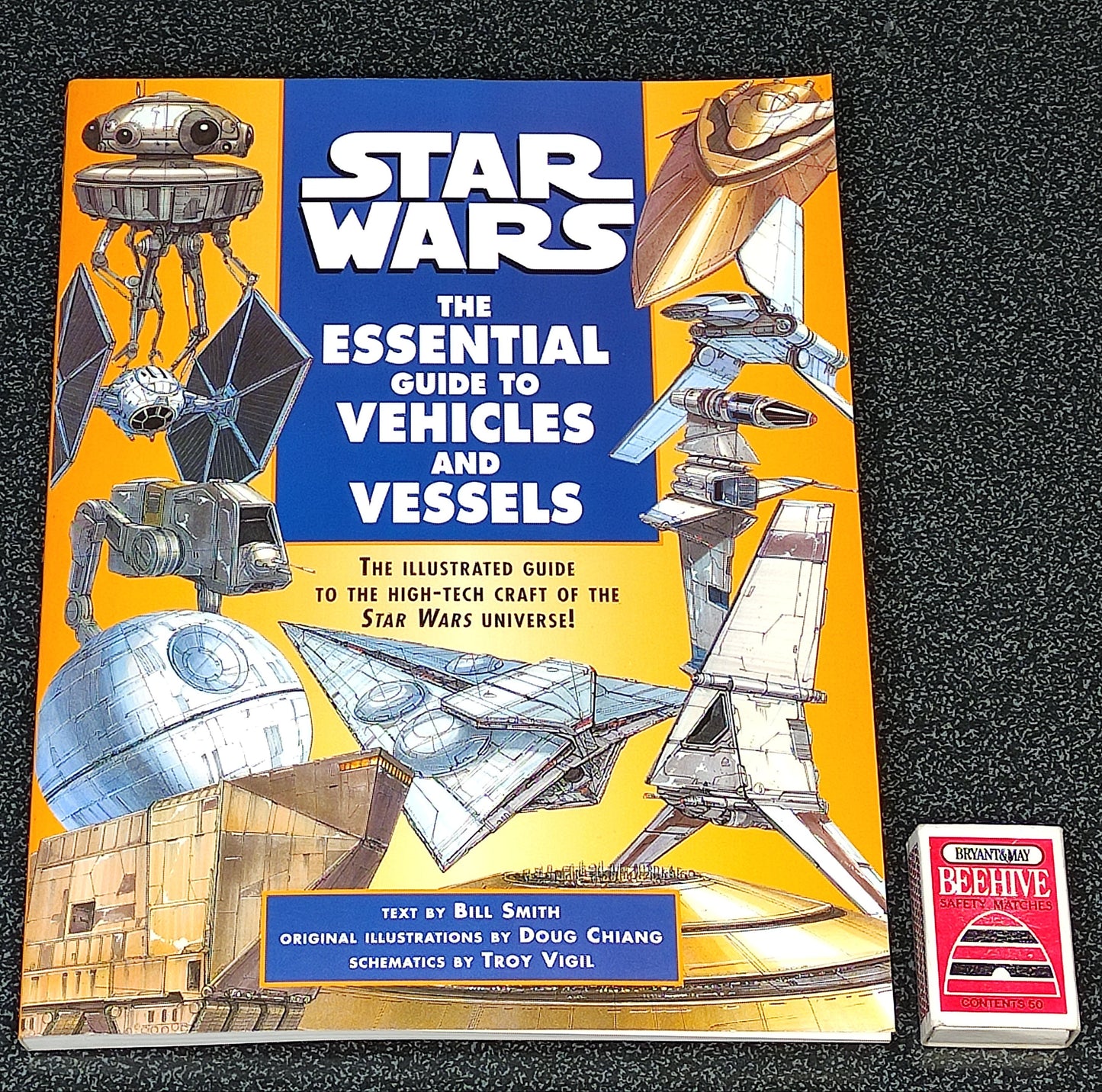 Book titled 'Star Wars: The Essential Guide to Vehicles and Vessels' on a dark textured background