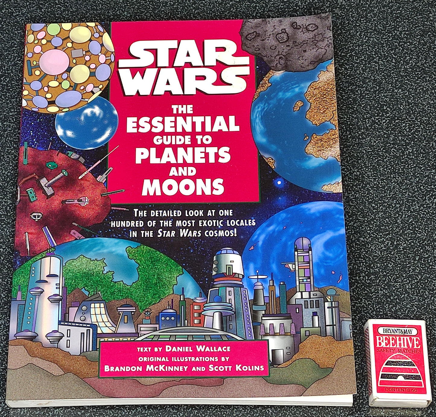 Book titled 'Star Wars: The Essential Guide to Planets and Moons' on a dark textured surface
