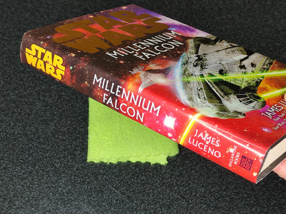 Book titled 'Millennium Falcon' by James Luceno on a dark surface with a green cloth underneath.