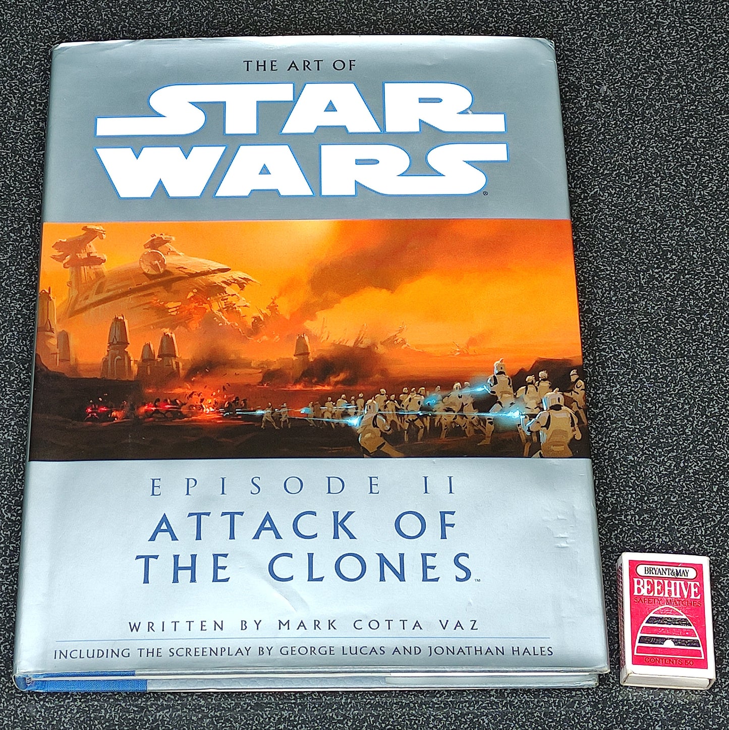Book titled 'The Art of Star Wars: Episode II Attack of the Clones' on a dark textured surface.