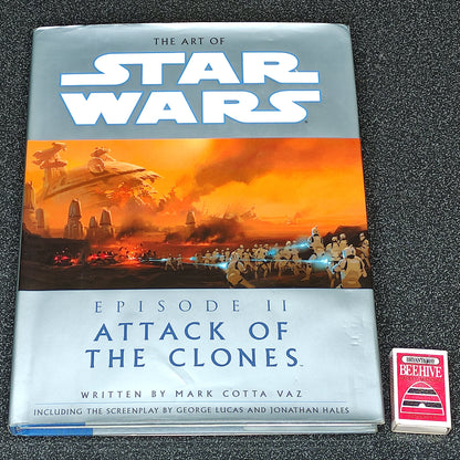 Book titled 'The Art of Star Wars: Episode II Attack of the Clones' on a dark textured surface.