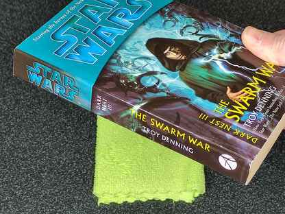 Book titled 'The Swarm War' by Troy Denning with a Star Wars branded book next to it on a dark surface.