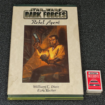 Book titled 'Star Wars: Dark Forces Rebel Agent' with a character illustration on the cover, placed next to a small red and white box.