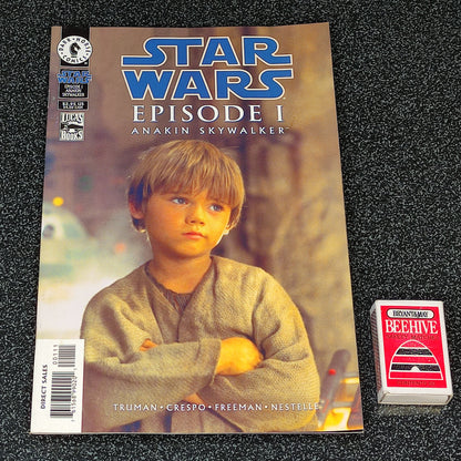 Comic book titled 'Star Wars Episode I: Anakin Skywalker' on a textured black surface with a small card beside it.