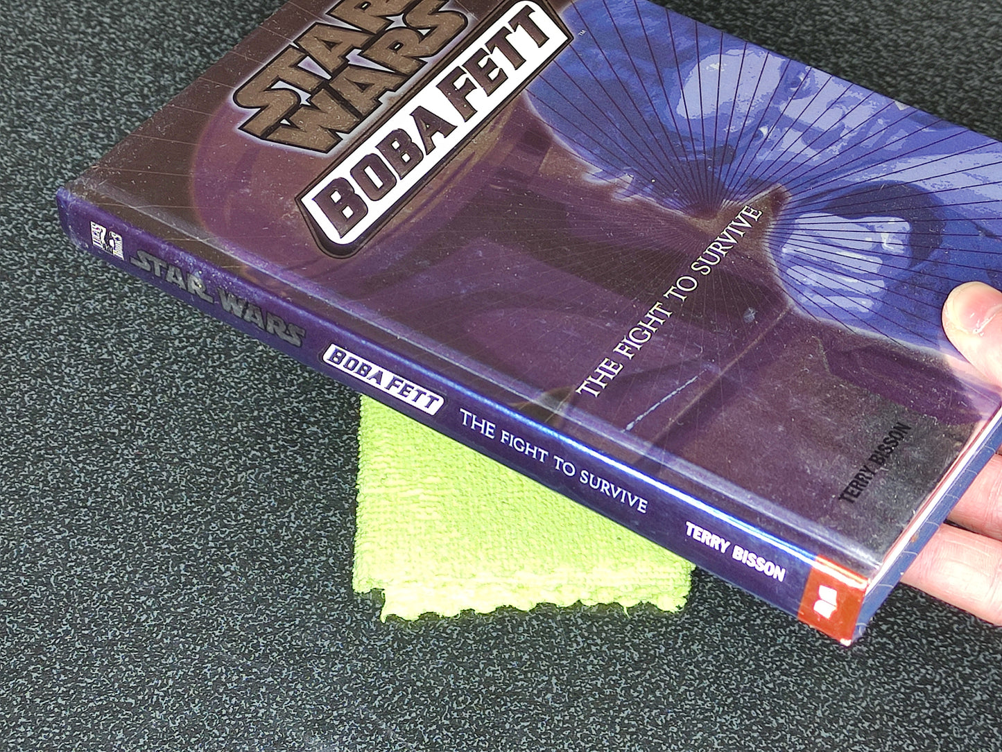 Book titled 'Boba Fett: The Fight to Survive' by Terry Bisson on a dark surface.