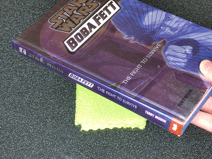 Book titled 'Boba Fett: The Fight to Survive' by Terry Bisson on a dark surface.