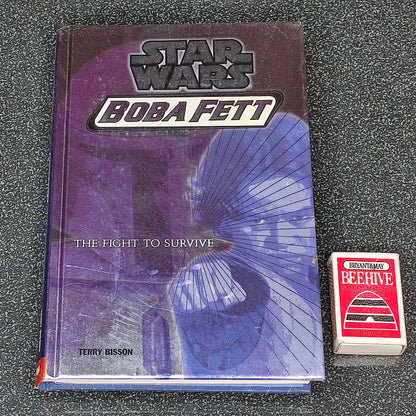 Star Wars Boba Fett book and a matchbox on a gray surface