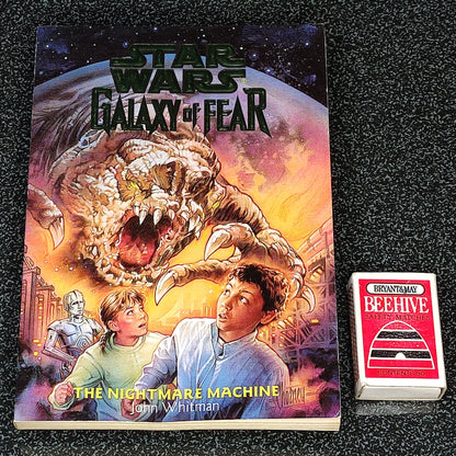 Book titled 'Star Wars: Galaxy of Fear' with a dragon and two children on the cover, next to a deck of cards.