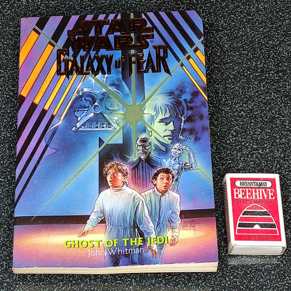 Book titled 'Star Wars Galaxy of Fear: Ghost of the Jedi' with a matchbox on a textured black surface