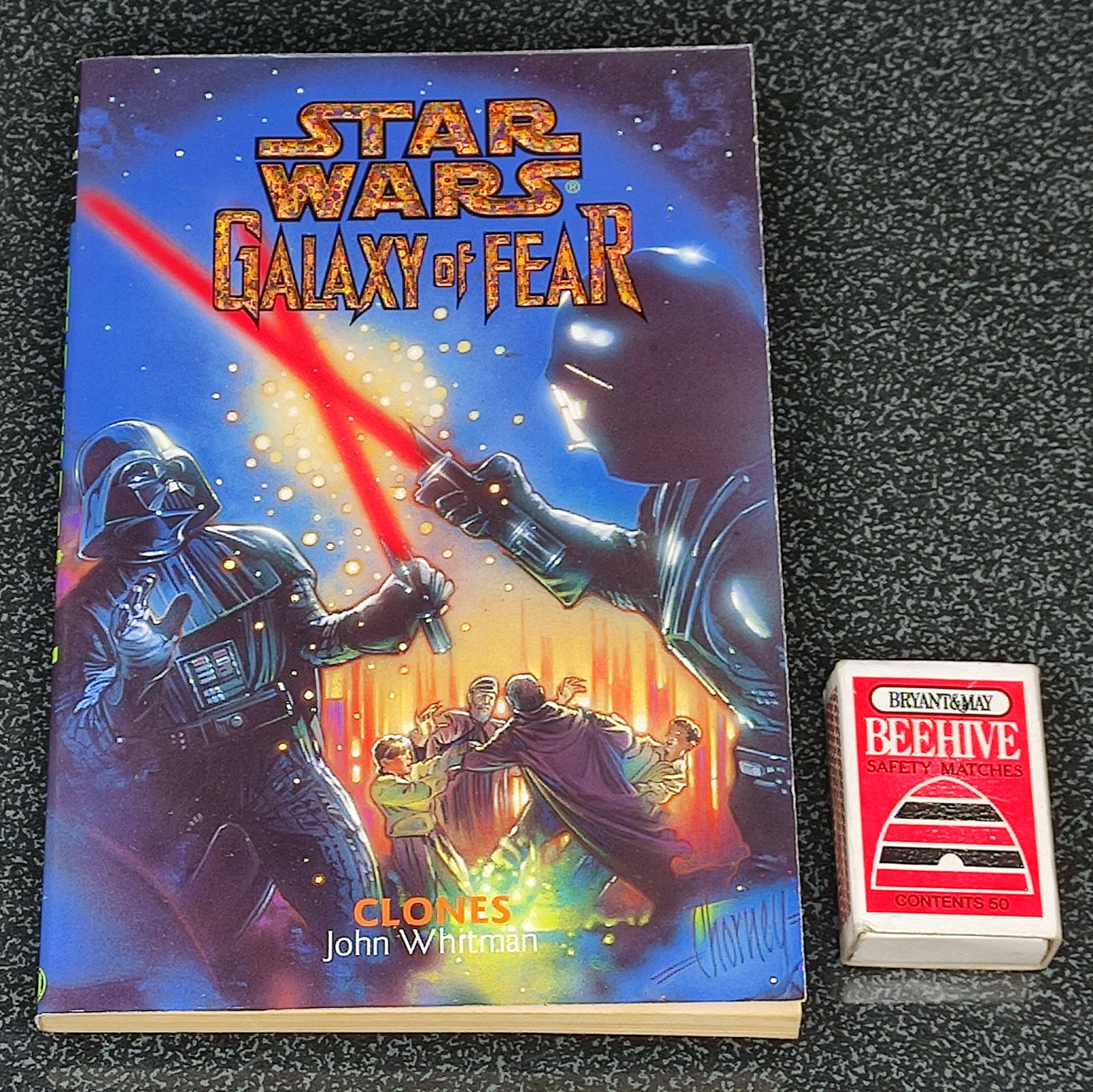 Book titled 'Star Wars: Galaxy of Fear' with a small red and white card on a dark textured surface