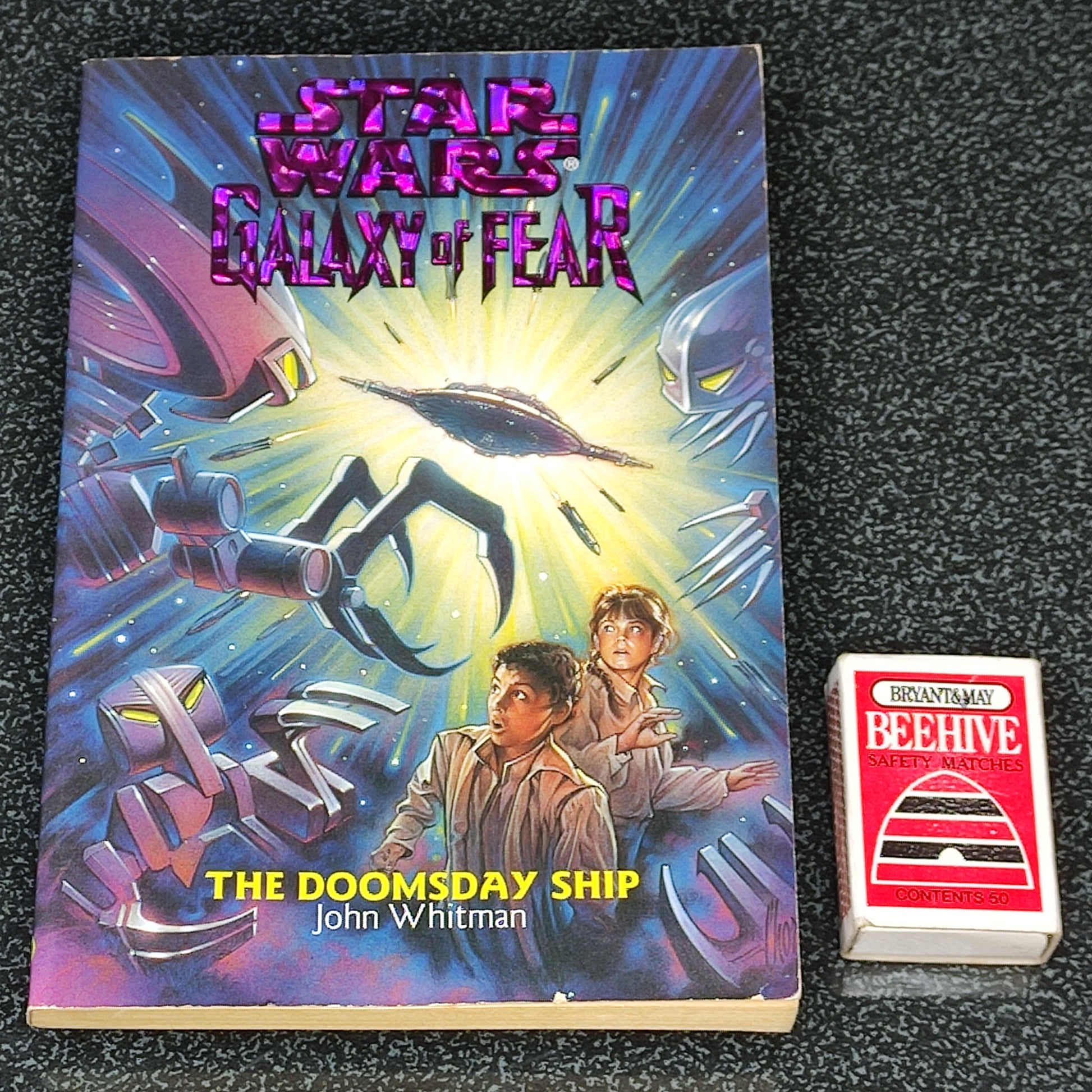 Book titled 'The Doomsday Ship' by John Whitman with a colorful cover featuring space-themed artwork on a dark textured background.