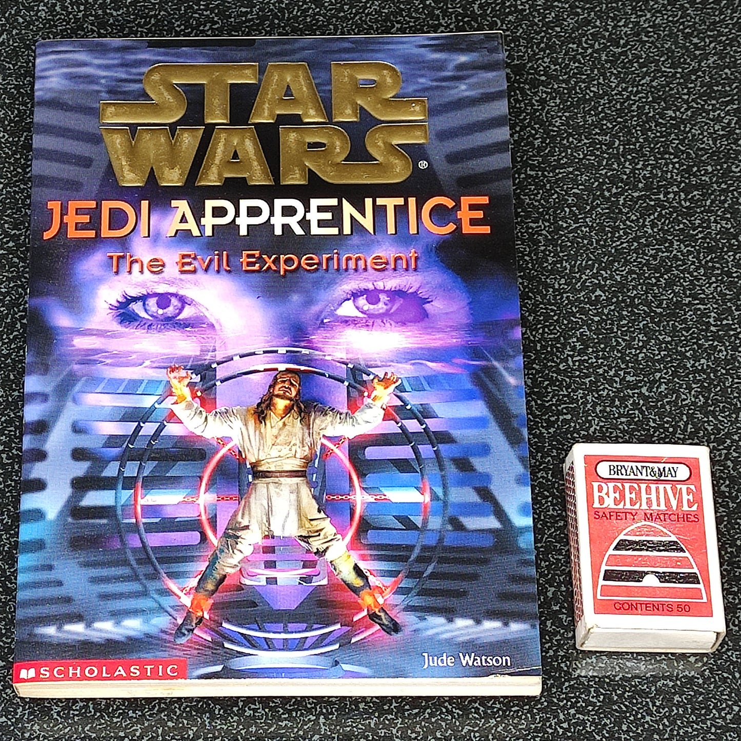 Book titled 'Star Wars Jedi Apprentice: The Evil Experiment' on a dark textured surface