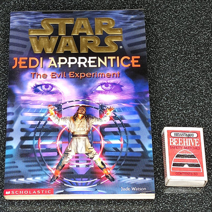 Book titled 'Star Wars Jedi Apprentice: The Evil Experiment' on a dark textured surface