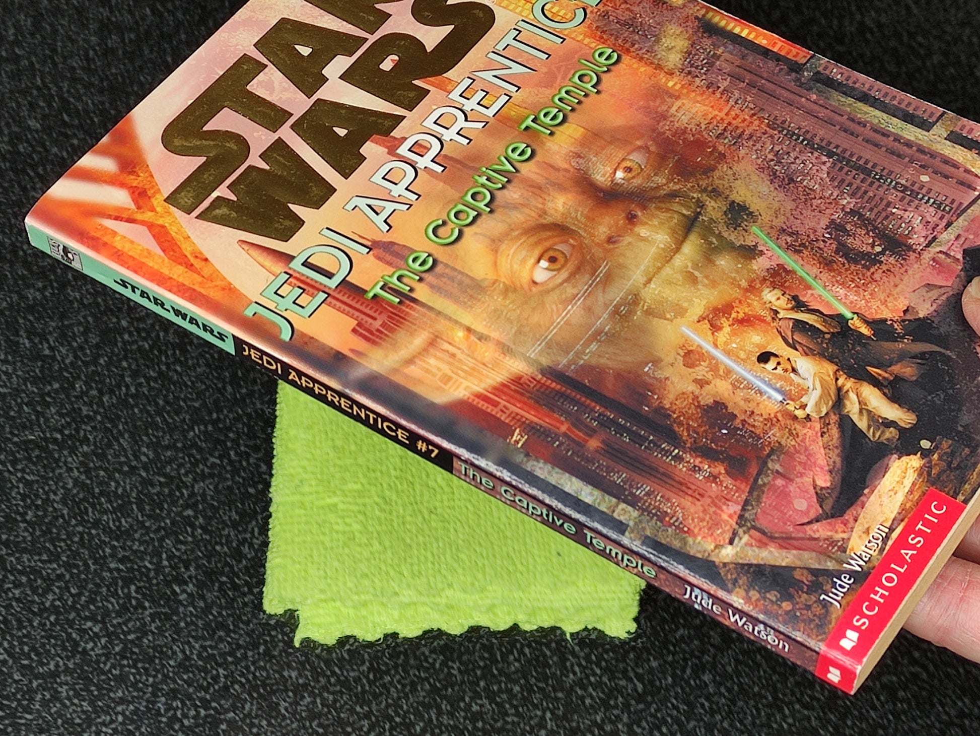 Book titled 'Jedi Apprentice: The Captive Temple' by Daniel Wallace on a dark textured surface with a green cloth underneath.