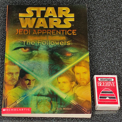 Book titled 'Star Wars Jedi Apprentice: The Followers' by Scholastic on a dark textured surface with a small box labeled 'Beehive' next to it.