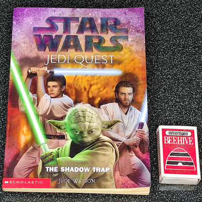 Star Wars Jedi Quest book with Yoda and two characters holding lightsabers on a textured black surface.