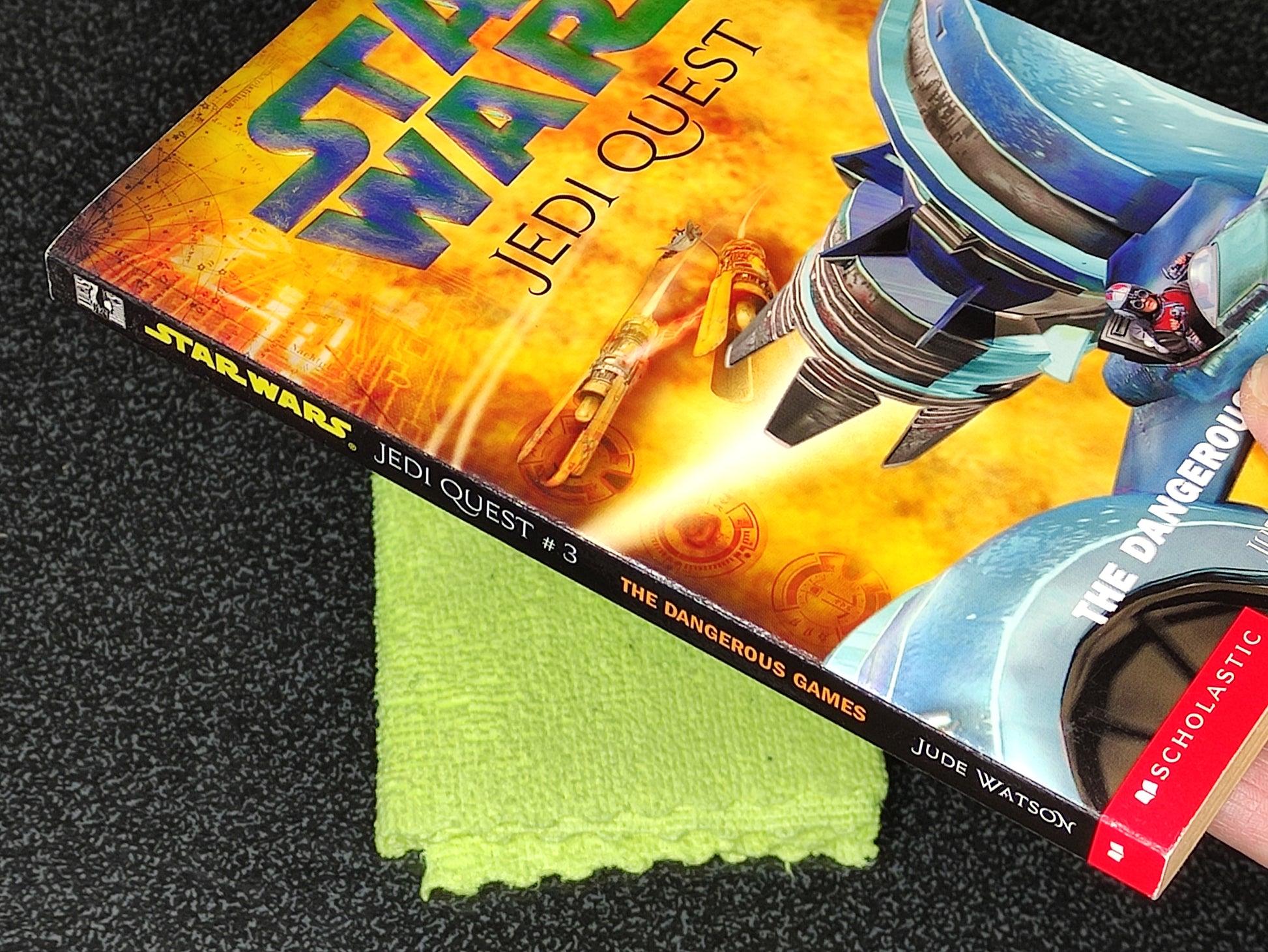 Book titled 'Star Wars Jedi Quest: The Dangerous Games' by Jude Watson on a textured surface.