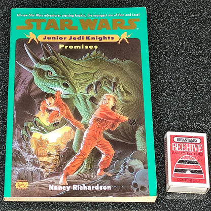 Star Wars Junior Jedi Knights book titled 'Promises' on a dark textured surface with a small card beside it.